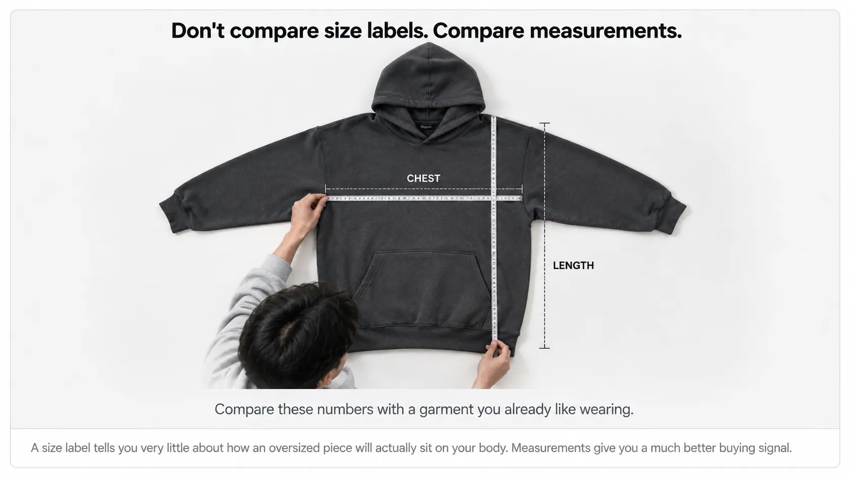 Person measuring the chest and length of an oversized hoodie before choosing a Decarba size